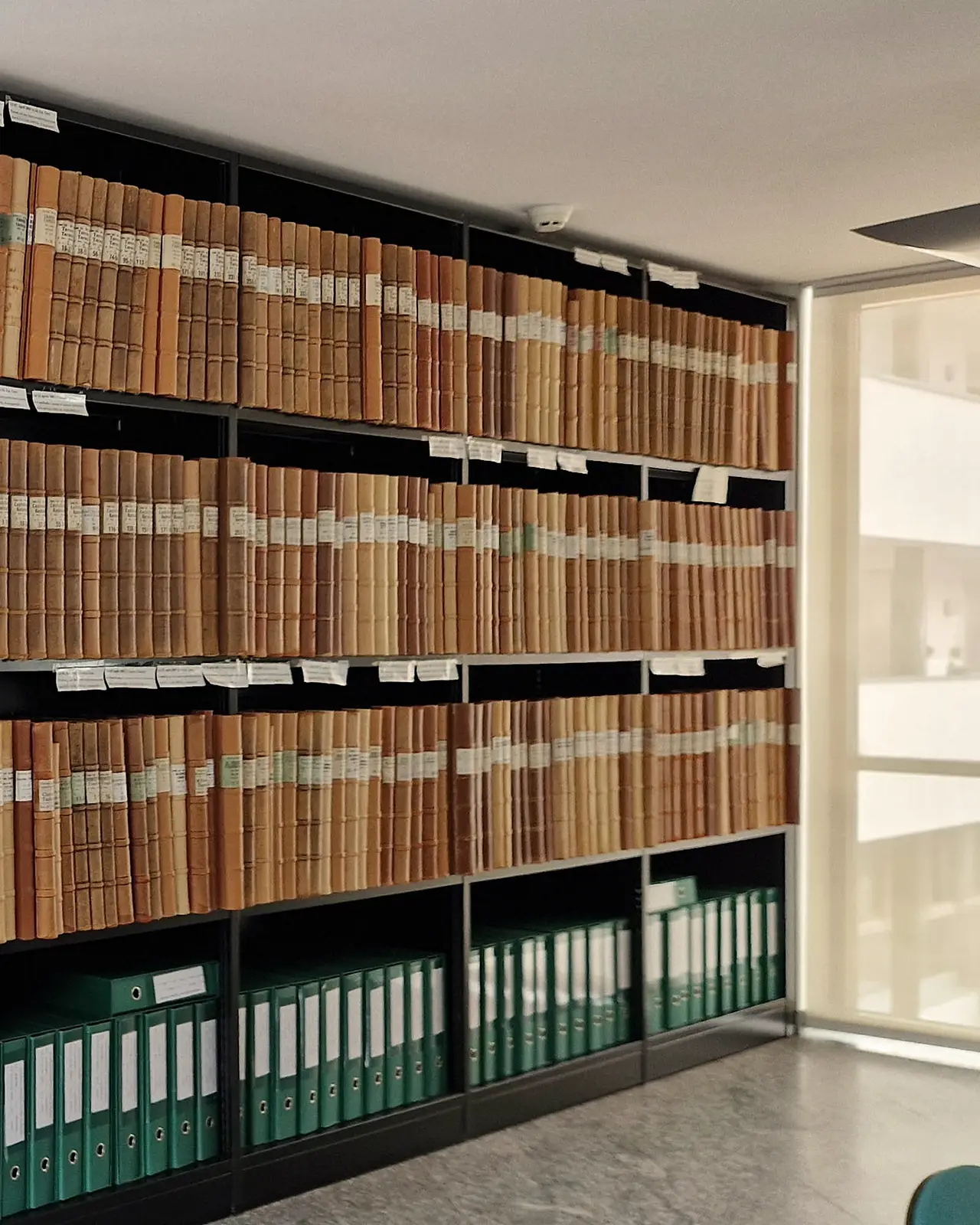 Notary Shelf Detail (Web) Detail of a South Tyrol Grundbuch shelf with numbered section tags and rows of bound land register volumes
